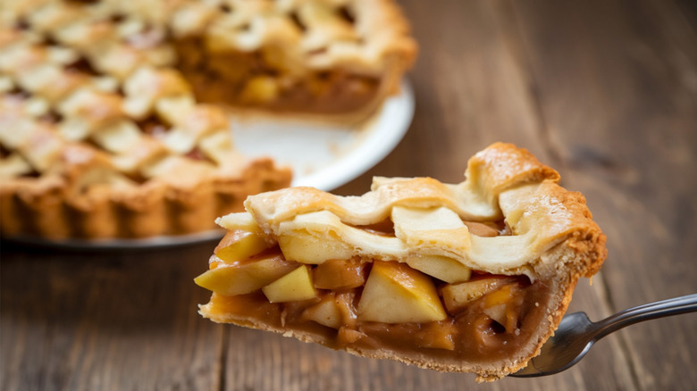 A slice of apple pie balanced on a spatula.