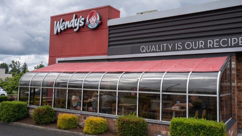 The exterior of a Wendy's sunroom with people dining in the restaurant.