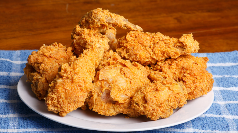 fried chicken pieces on a white plate on top of a blue-and-white striped cloth