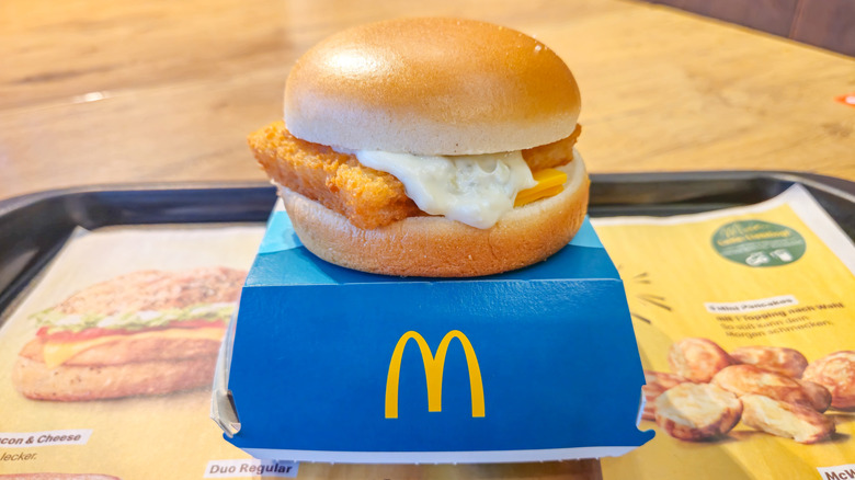 McDonald's Filet-O-Fish sandwich sitting on top of its blue box with the yellow logo on a tray
