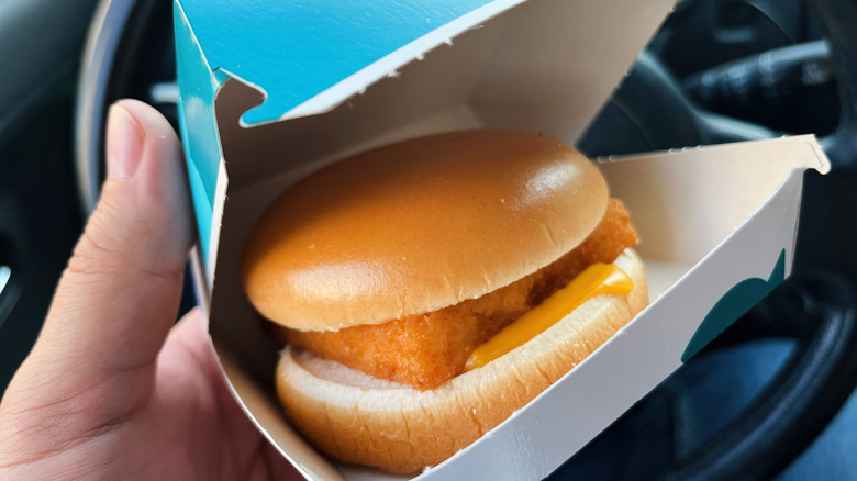 Hand holding a open McDonald's box with a Filet-o-Fish inside in a car