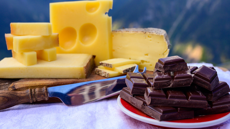 Blocks of cheese alongside a plate of chocolate.