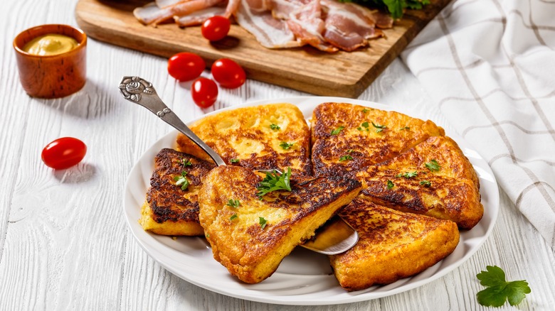 Plate of potato farls cut into triangles with bacon slices, mustard, and cherry tomatoes in the background