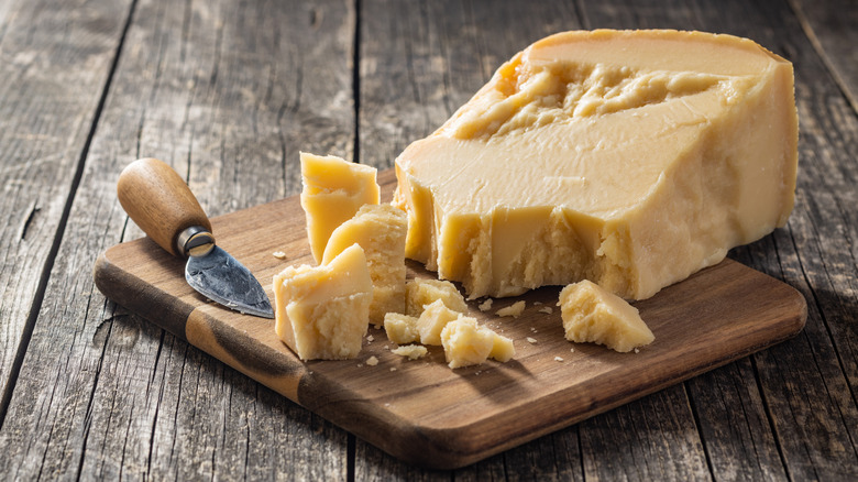 A crumbled slice of Parmigiano Reggiano on a cutting board