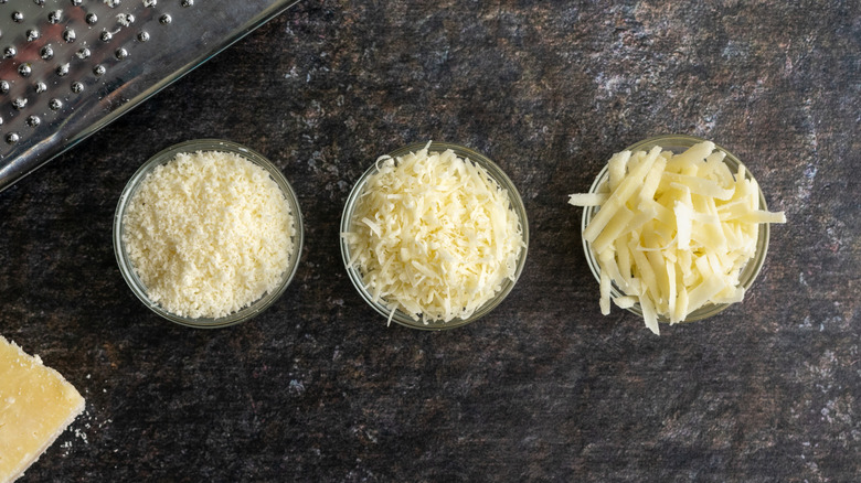 Three small glass bowls of different types of parmesan cheese