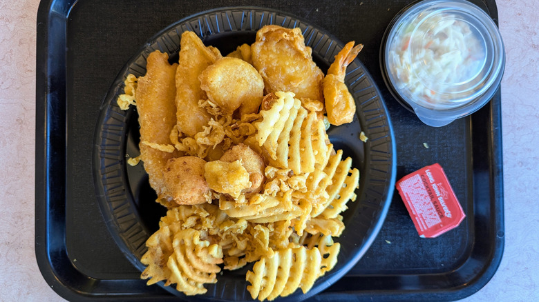 A plate of fish and waffle fires at Long John Silver's with a side of coleslaw and some dipping sauce.