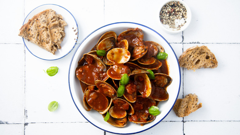 Clams in tomato sauce, served with bread and crushed pepper.