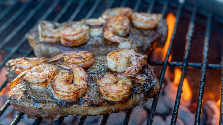 Steaks topped with shrimp on a charcoal grill