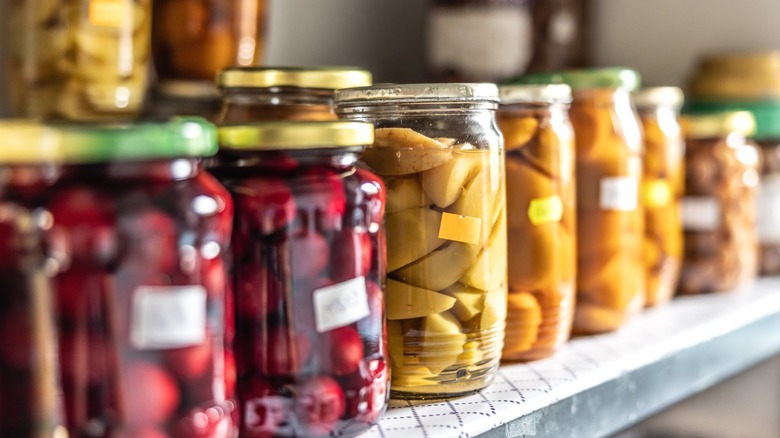 A shelf full of pickled food items in mason jars