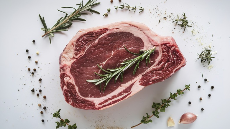 Raw steak surrounded by various herbs and spices.