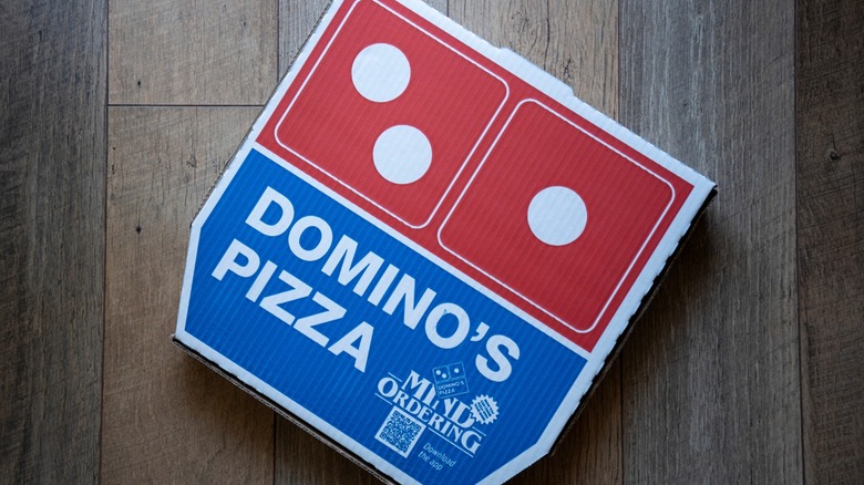 A close-up on a Domino's pizza box, prominently featuring its logo.