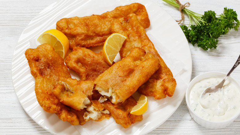Deep-fried fish fillets on a white plate with lemon and tartar sauce
