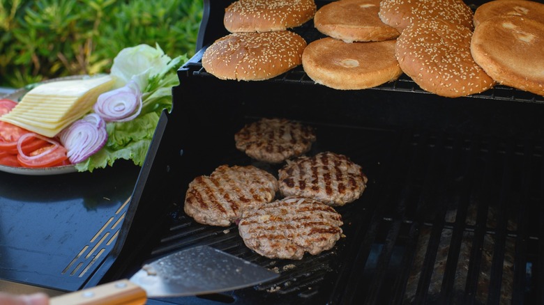 Using a spatula to flip burgers on a grill