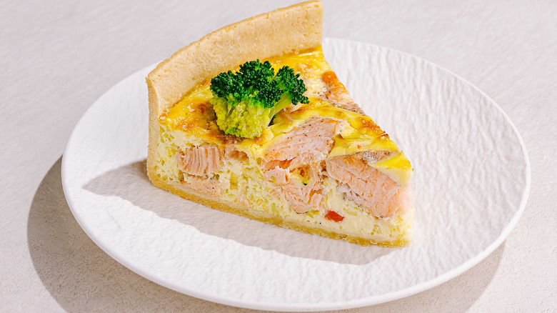 Slice of salmon quiche on a white plate