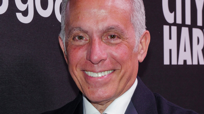 Geoffrey Zakarian smiling in front of a black backdrop