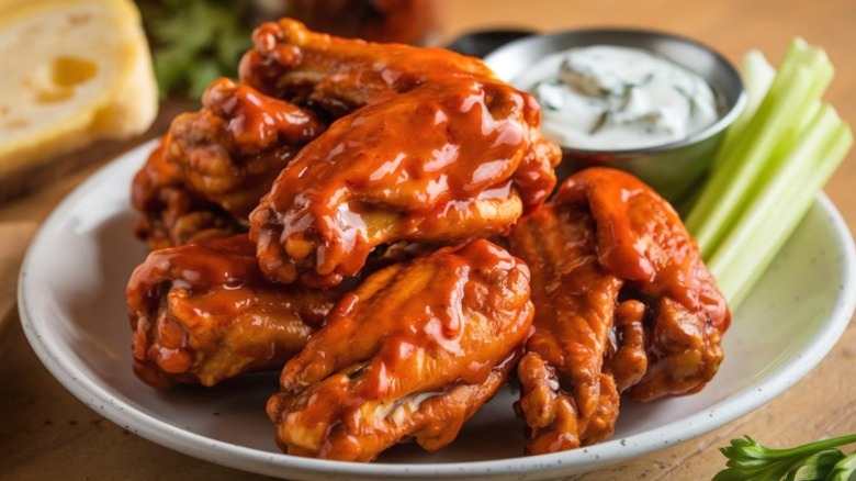 A plate of buffalo wings with blue cheese and celery.