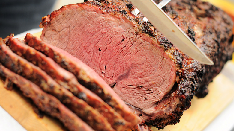 Slicing prime rib on a wooden cutting board