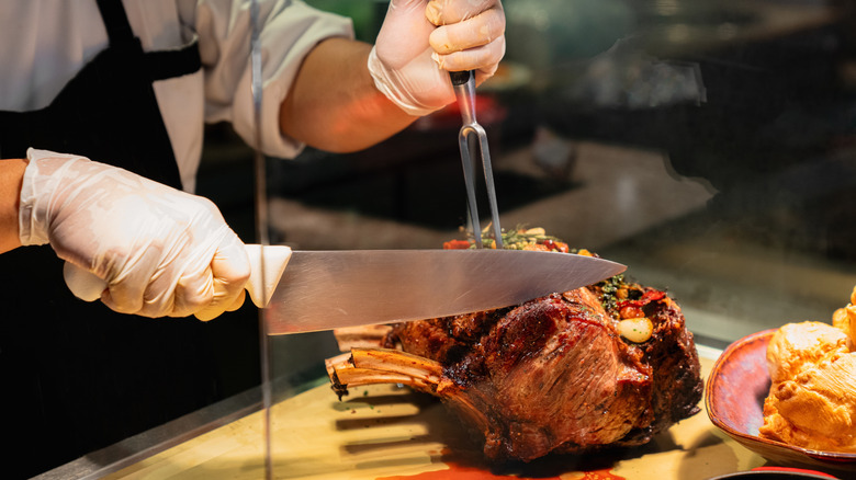 A chef carves roasted bone-in prime rib for guests