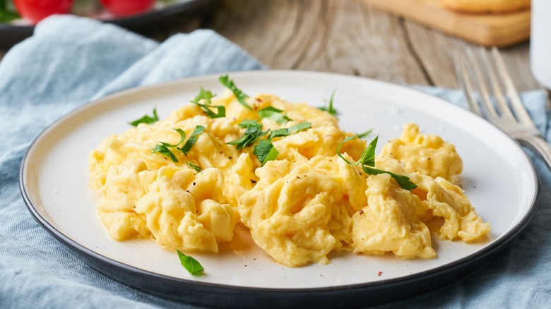 Scrambled eggs with herb garnish on white plate