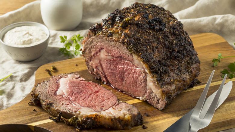 cooked prime rib partially sliced on a wooden board