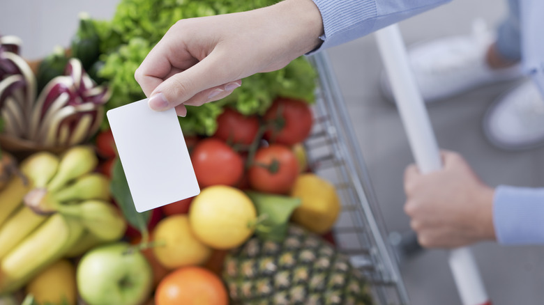 Hand holding card while grocery shopping