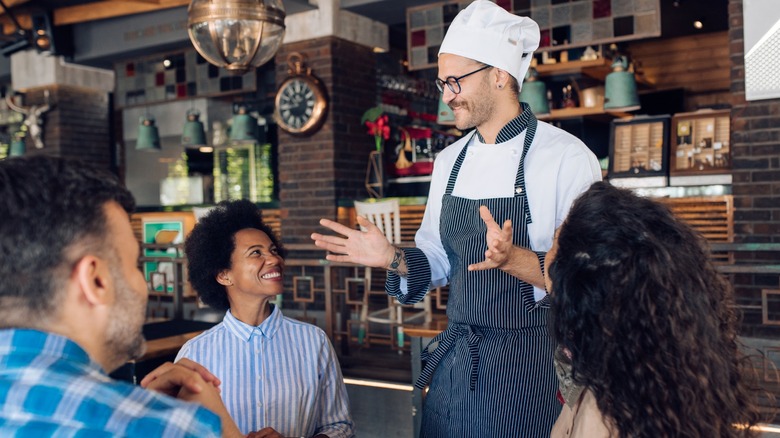 Chef speaking with customers at table