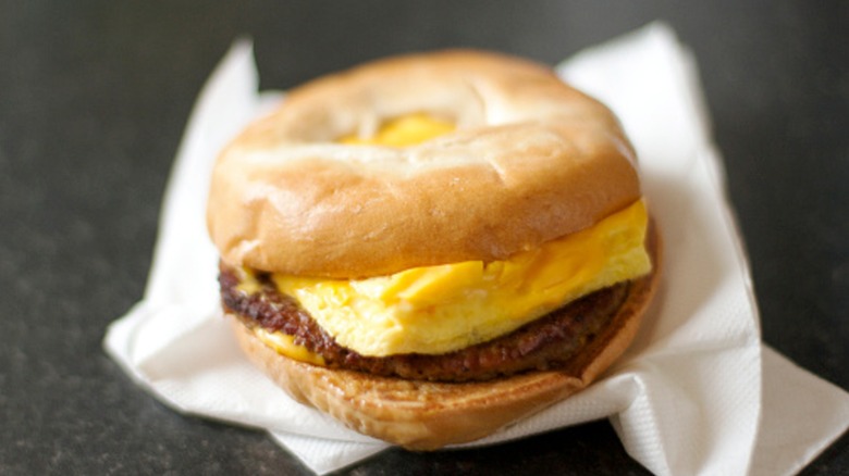 A bagel sandwich with egg, cheese, sausage patty on a napkin