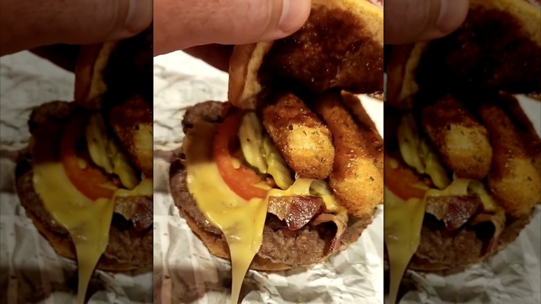 Lifting the bun on a Sheetz custom Big Mozz burger with pickles and bacon