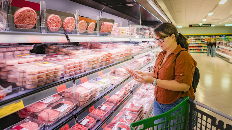 Woman looking at meat in the supermarket meat aisle.