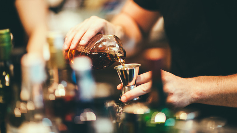 bartender pours a jigger of bourbon