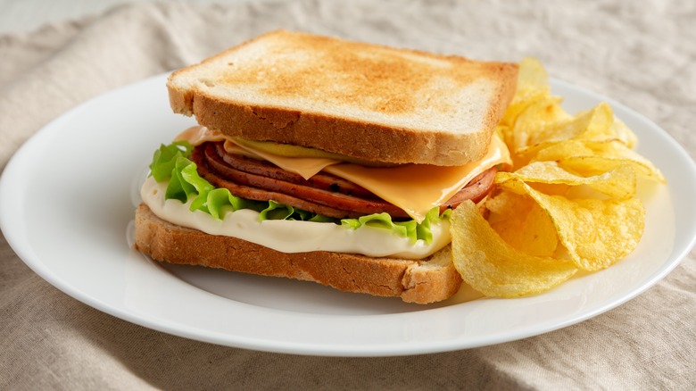 fried bologna and cheese sandwich with chips on plate