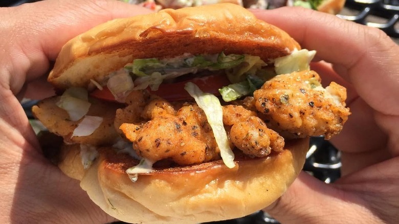hands holding fried walleye sandwich