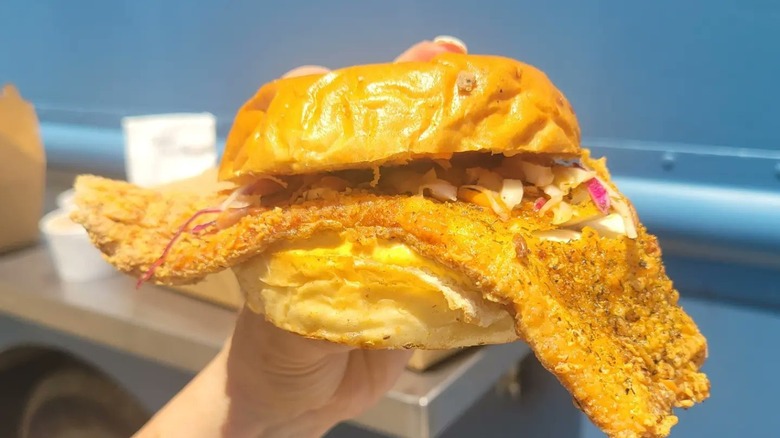 hand holding fried trout sandwich