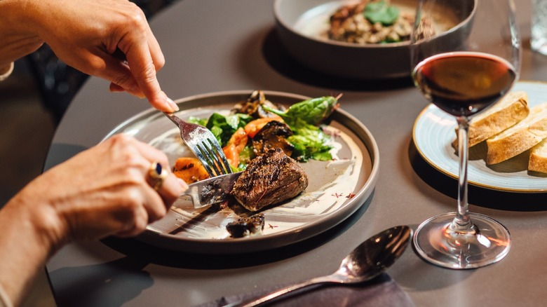 A person eating a steak dinner at a table