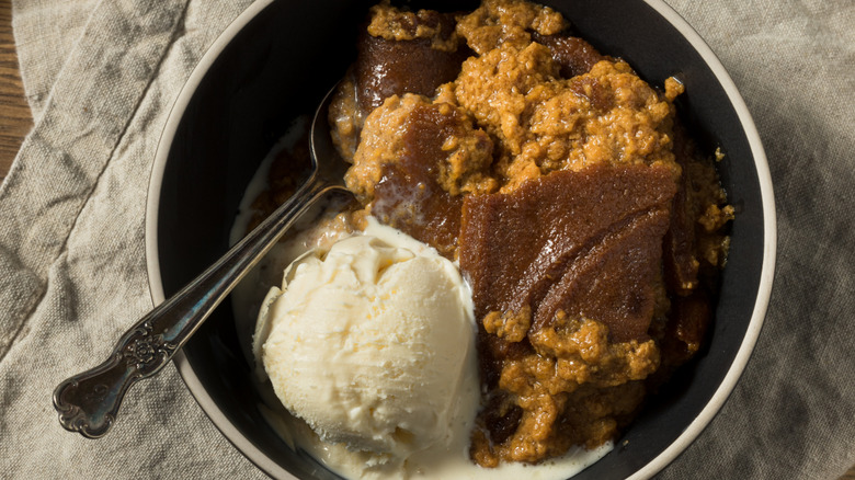 Indian pudding in a bowl with vanilla ice cream