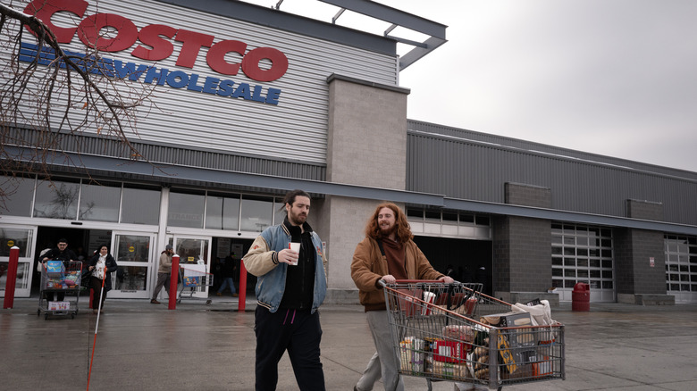 Two men walking out of a Costco with a shopping cart full of groceries