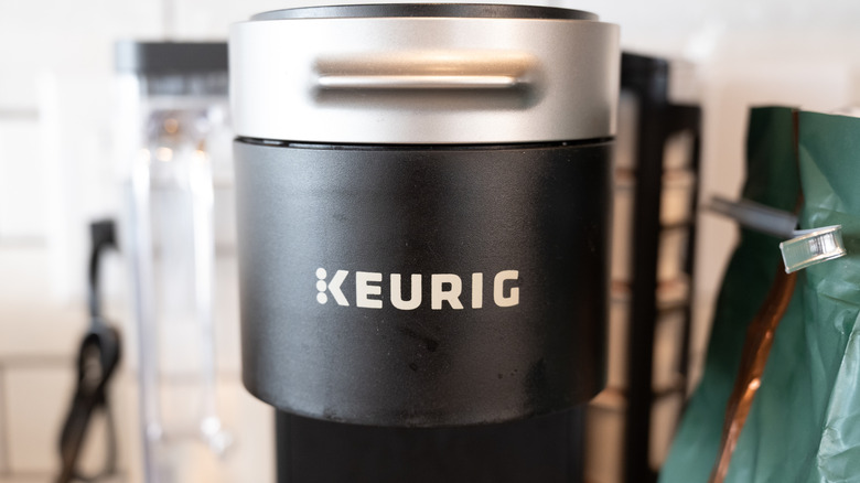 A Keurig Coffee Maker beside a bag of coffee on a kitchen counter
