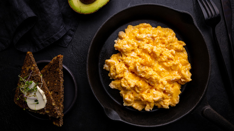 Scrambled eggs in a cast iron pan with toast