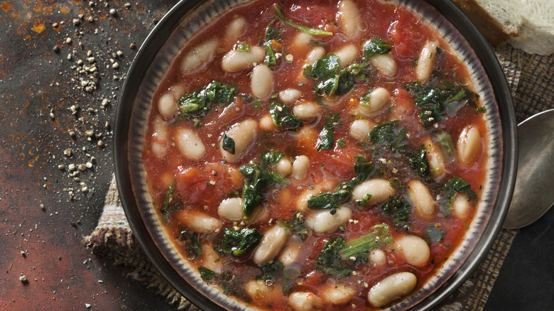 Bowl of tomato based soup with greens and white beans
