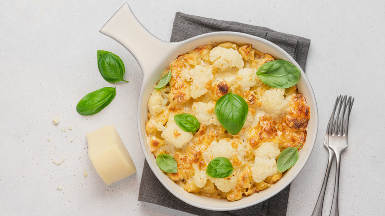 Top view of baked cauliflower mac and cheese with basil leaves