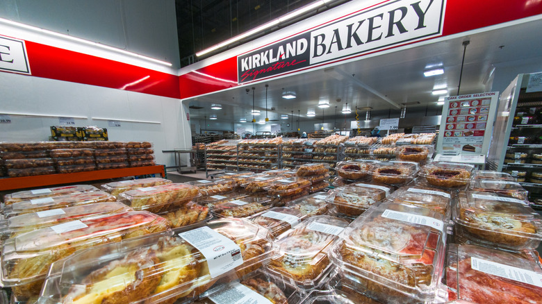 Costco bakery with Kirkland Signature Bakery sign hanging above pastry-filled tables and shelves
