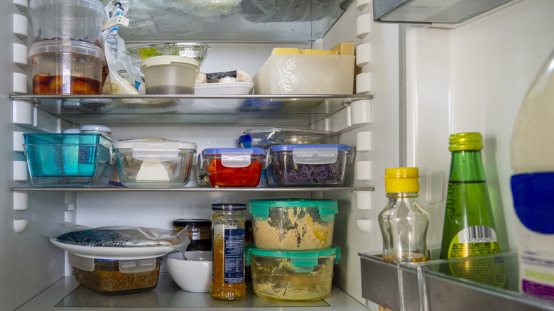 Open fridge with leftover food in storage containers