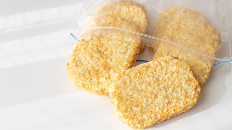 Frozen hash brown patties falling out of a plastic Ziploc bag