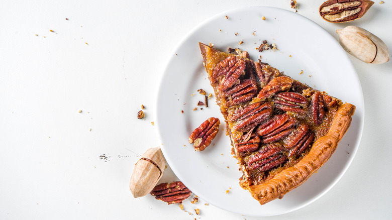 Top view of a slice of pecan pie on white plate