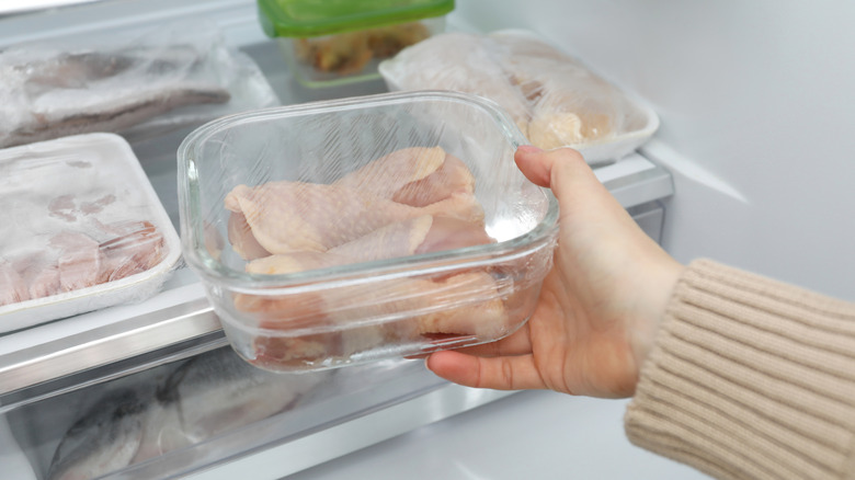 Raw chicken in containers on the bottom fridge shelf