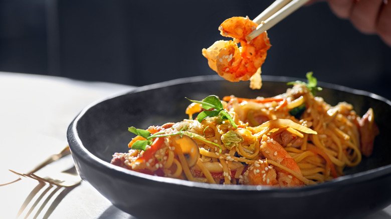 hand holding shrimp with chopsticks