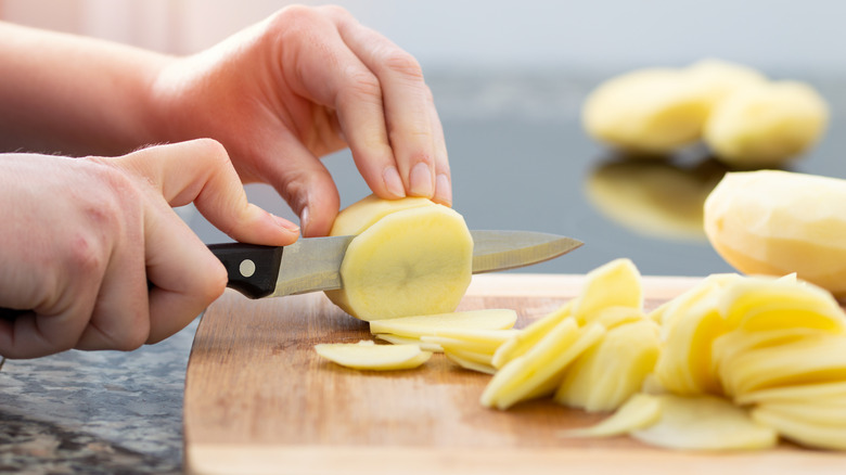Close up of hands slicing potatoes