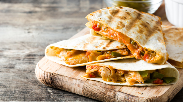 Cheesy chicken quesadillas on wooden cutting board