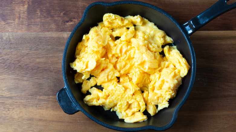 A small black skillet filled with fluffy scrambled eggs