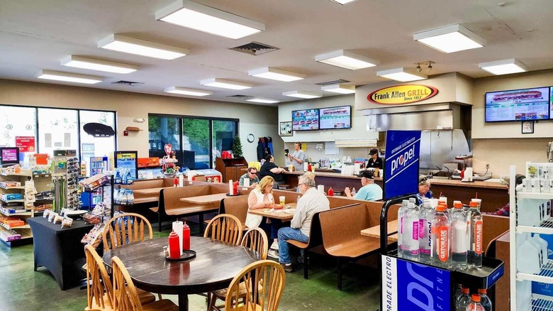 Inside of diner showing people in booths and a Frank Allen Grill sign
